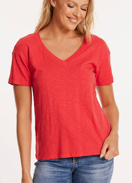 A woman wearing a red v-neck t-shirt and blue jeans.
