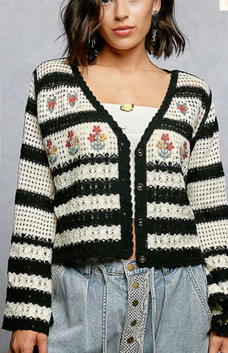 Woman wearing a black and white striped cardigan with floral patterns on a gray background