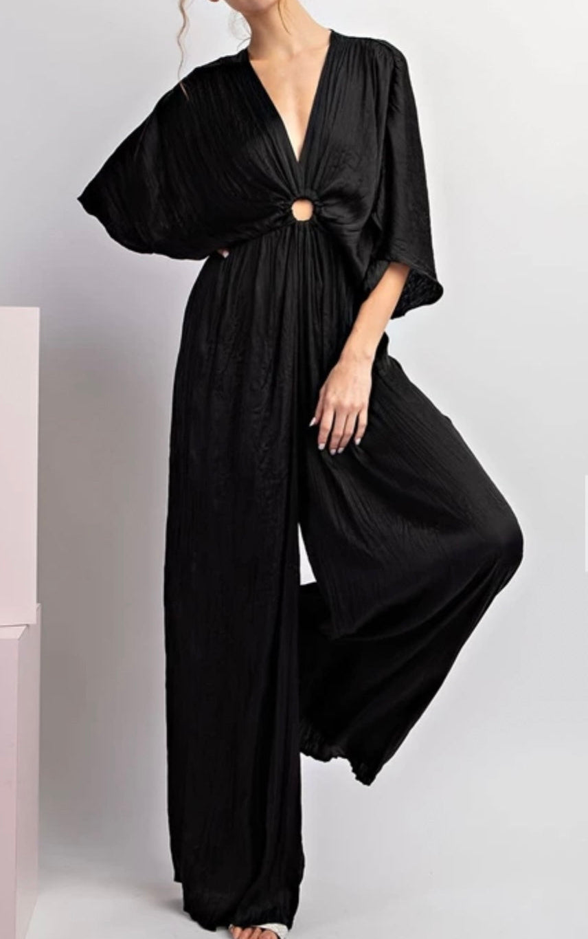 Woman wearing a black jumpsuit on a light gray background