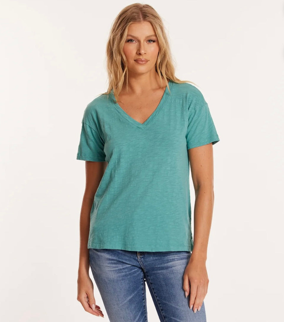 A woman wearing a blue v-neck t-shirt and blue jeans.